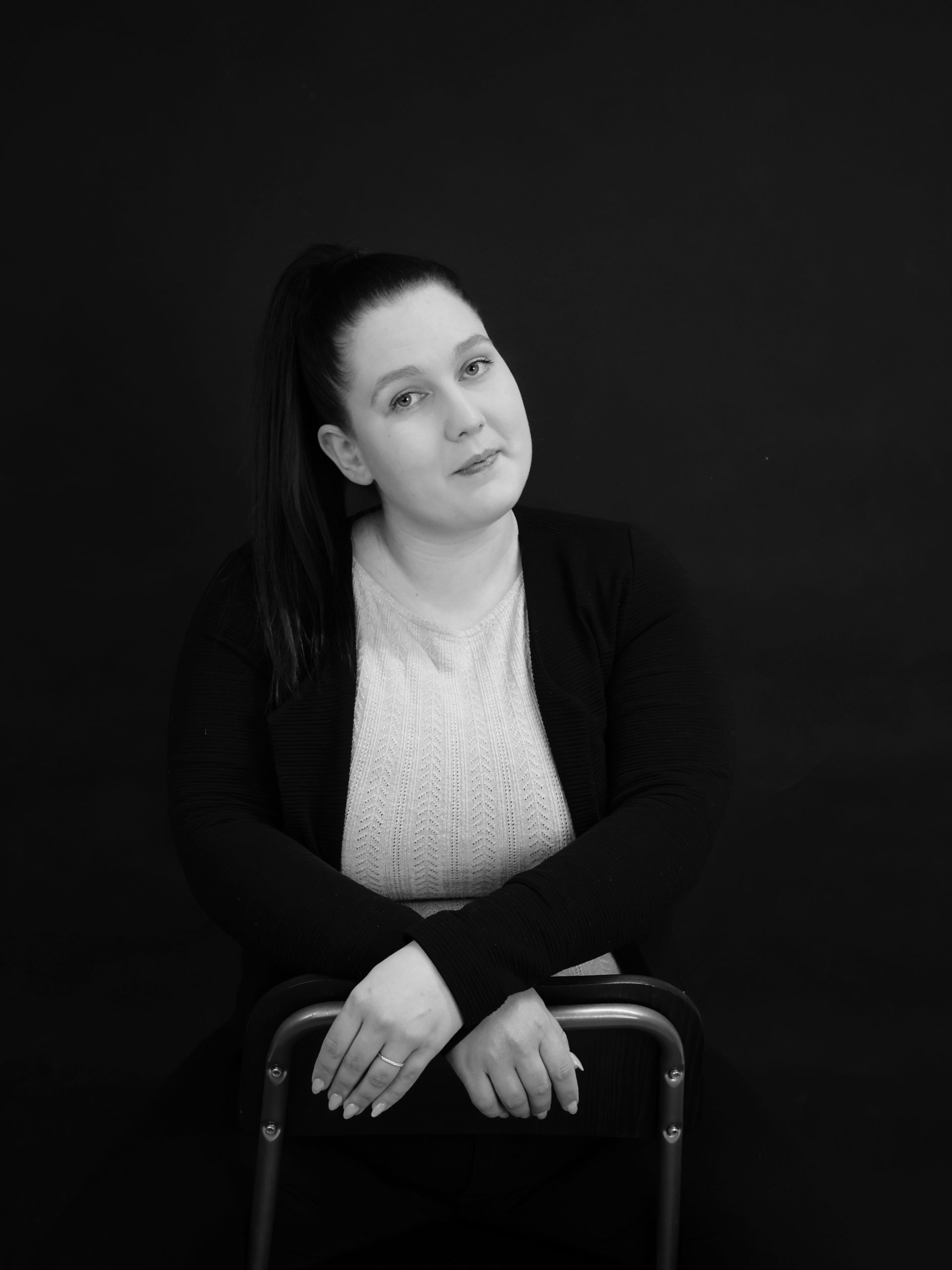 Henkilökuva nainen istumassa tuolilla kädet selkänojan päällä.